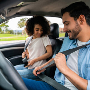 Young Latin American couple in a car fastening their seat belts - transportation concepts