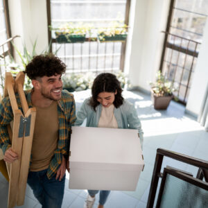 High angle view of a young Caucasian couple moving into their new place together, carrying their stuff in, getting ready to reorganize their new apartment, smiling